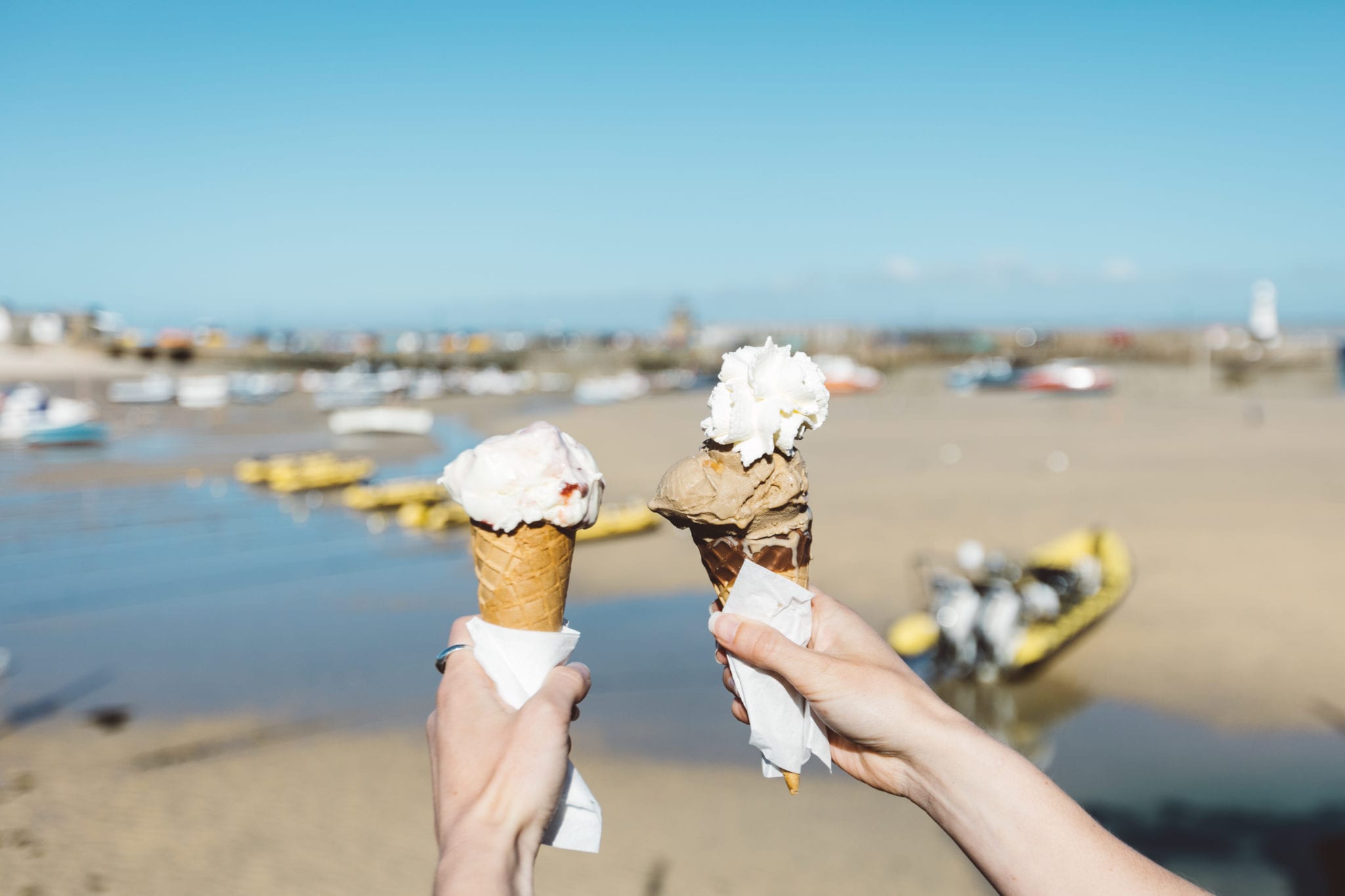 Two ice cream cones held up against St Ives harbour
