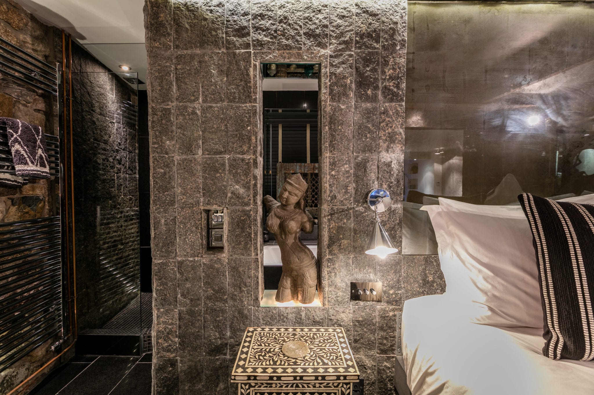 A bedroom with grey slate walls, balinese and moroccan features and low lighting