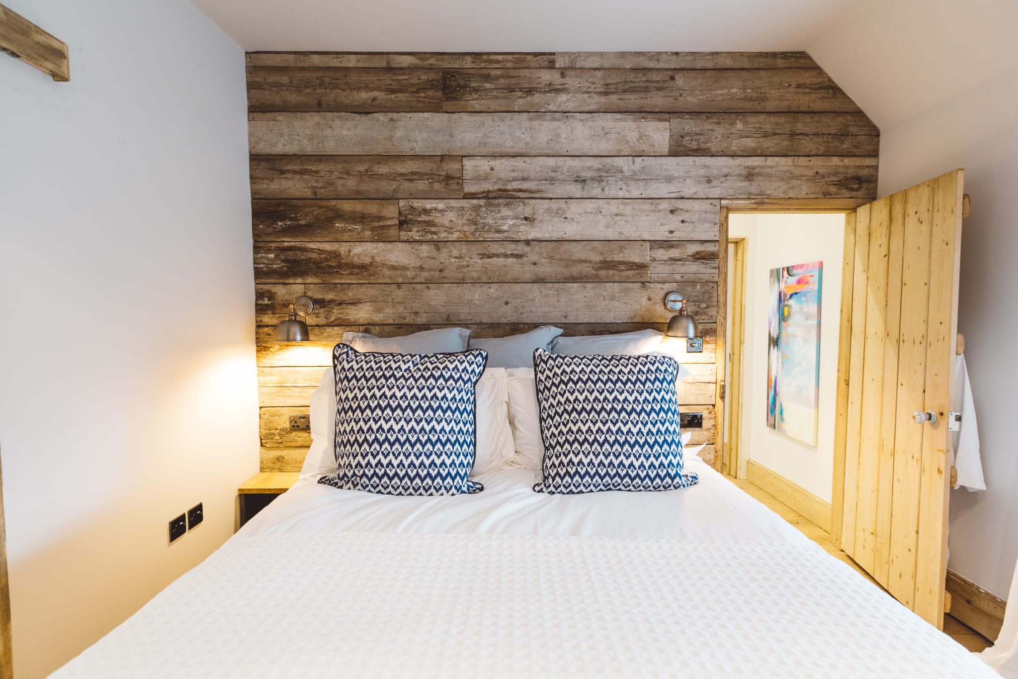 A stylish modern bedroom with a rustic wooden clad wall