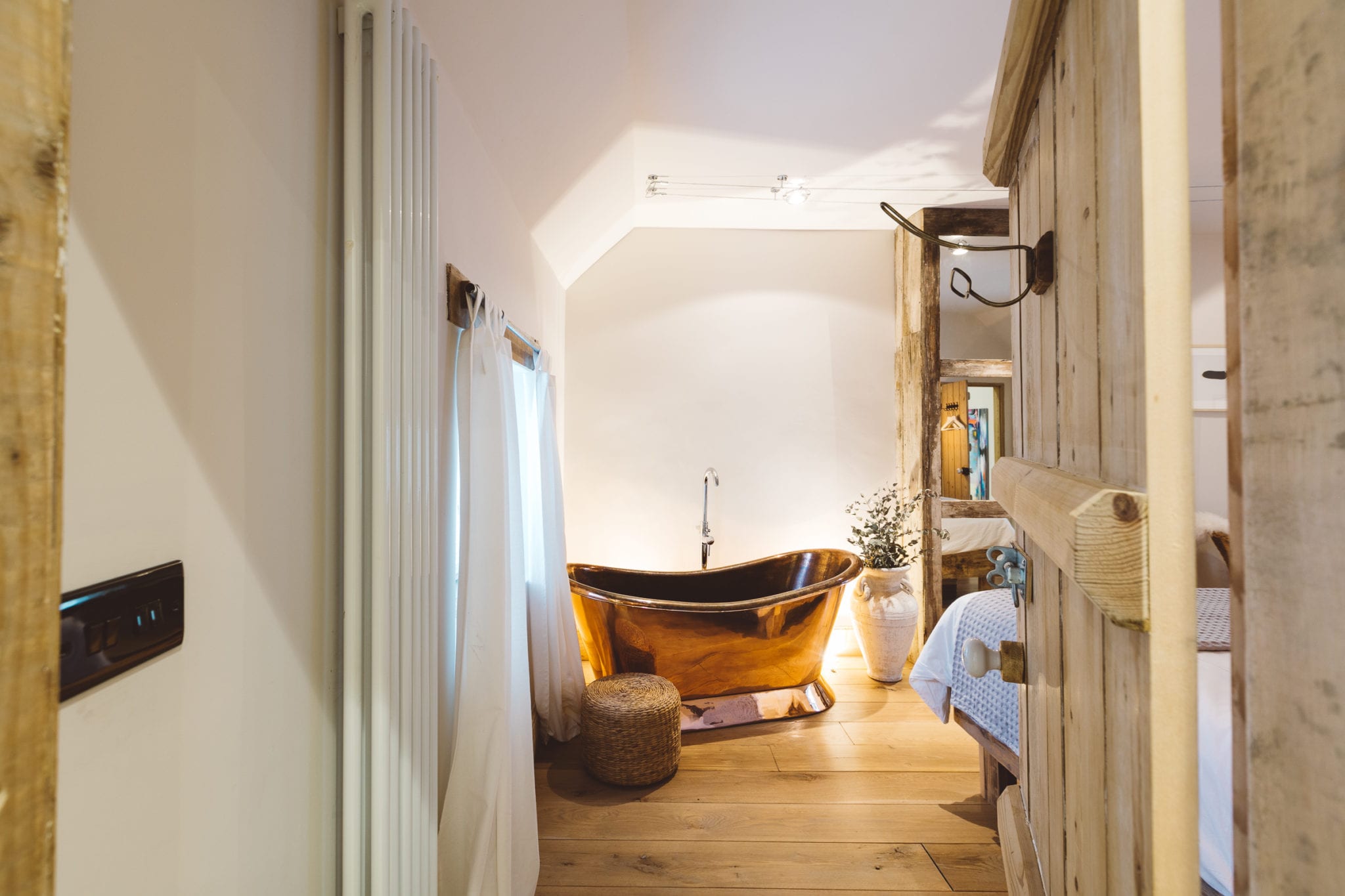 A large copper roll top bathtub in the corner of a bedroom