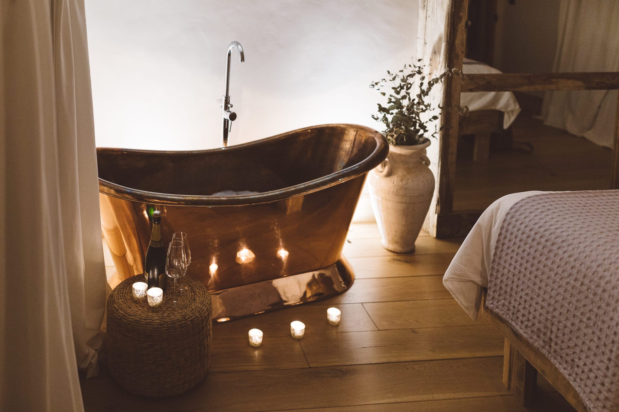 A copper roll top bath tub surrounded by candles