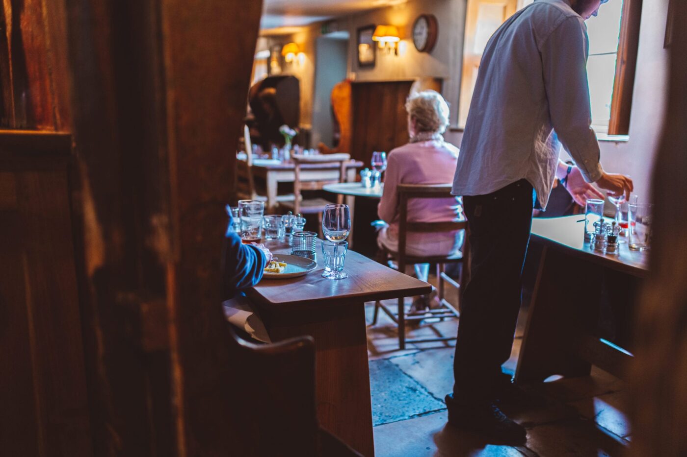 People sitting on chairs and wooden benches enjoying a drink in an old pub