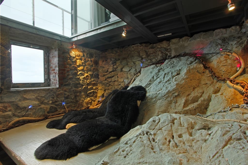 A cave with fur rugs, feature lighting and a window looking out to sea