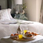 Close up shot of breakfast items on a wooden board by the bed