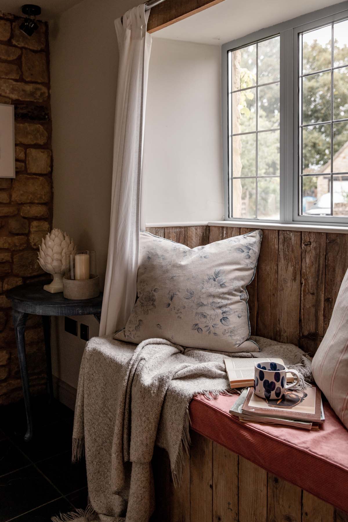 cosy windowsill seat with floral cushion, book and mug