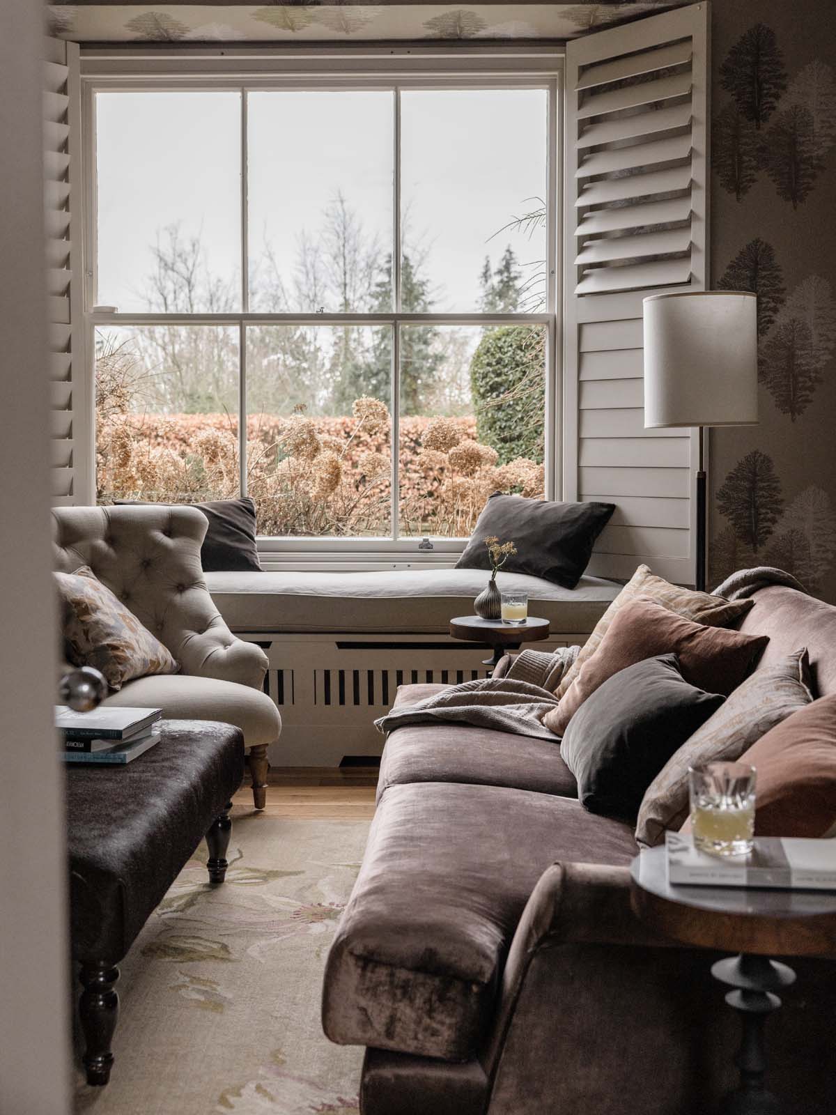 Luxurious living room with neutral soft furnishings and a large window with plantation shutters