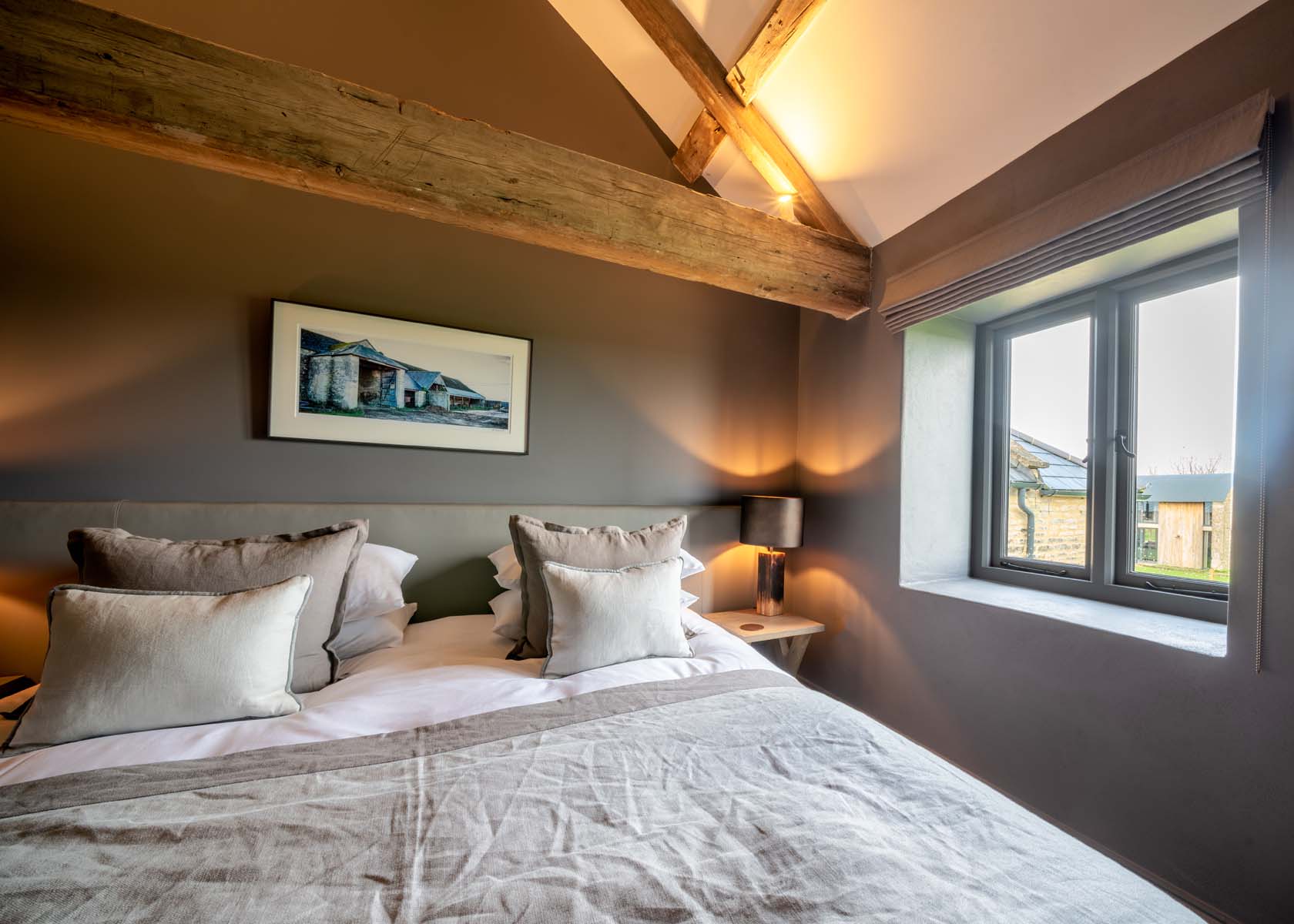 Double bedroom with grey walls and exposed wooden beams