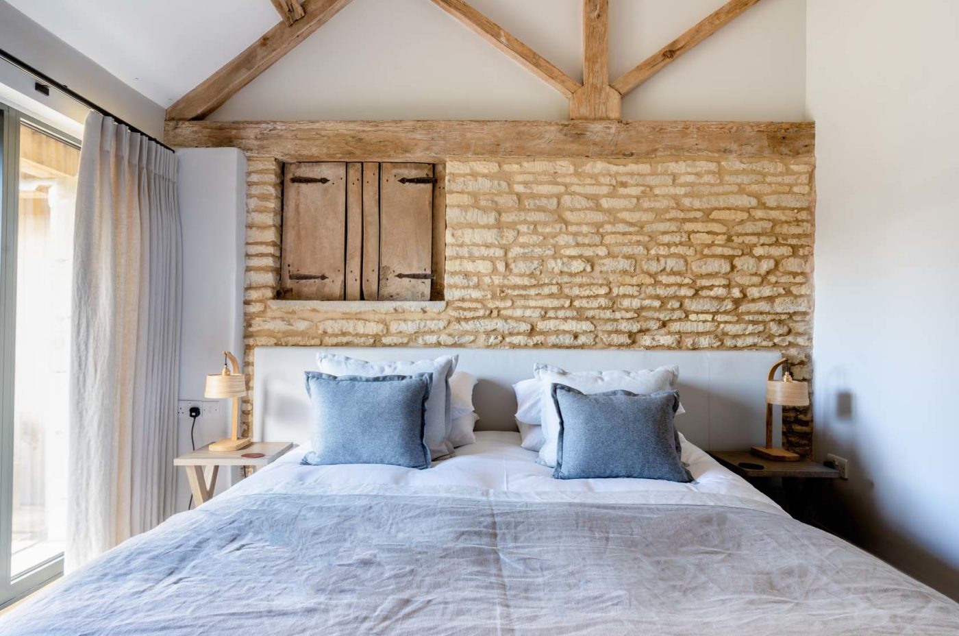 Large double bedroom with exposed brick work and high ceilings with wooden beams