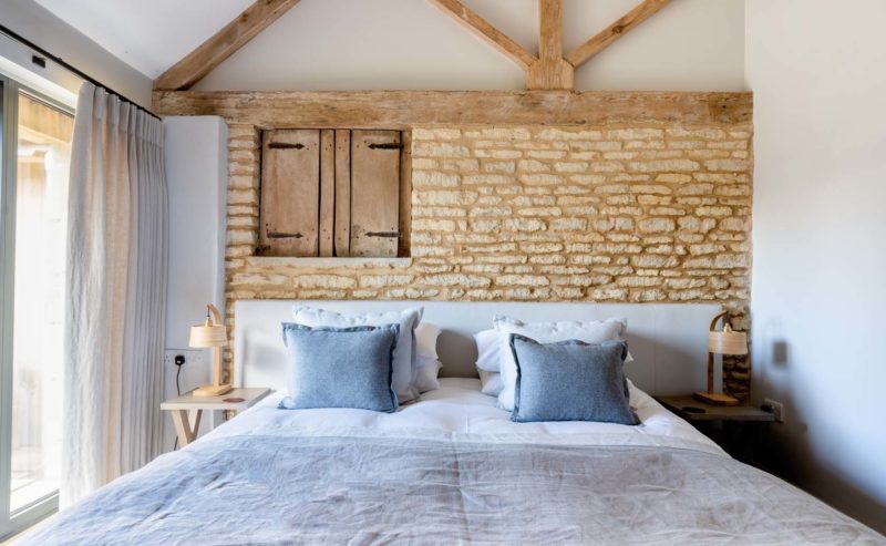 Large double bedroom with exposed brick work and high ceilings with wooden beams
