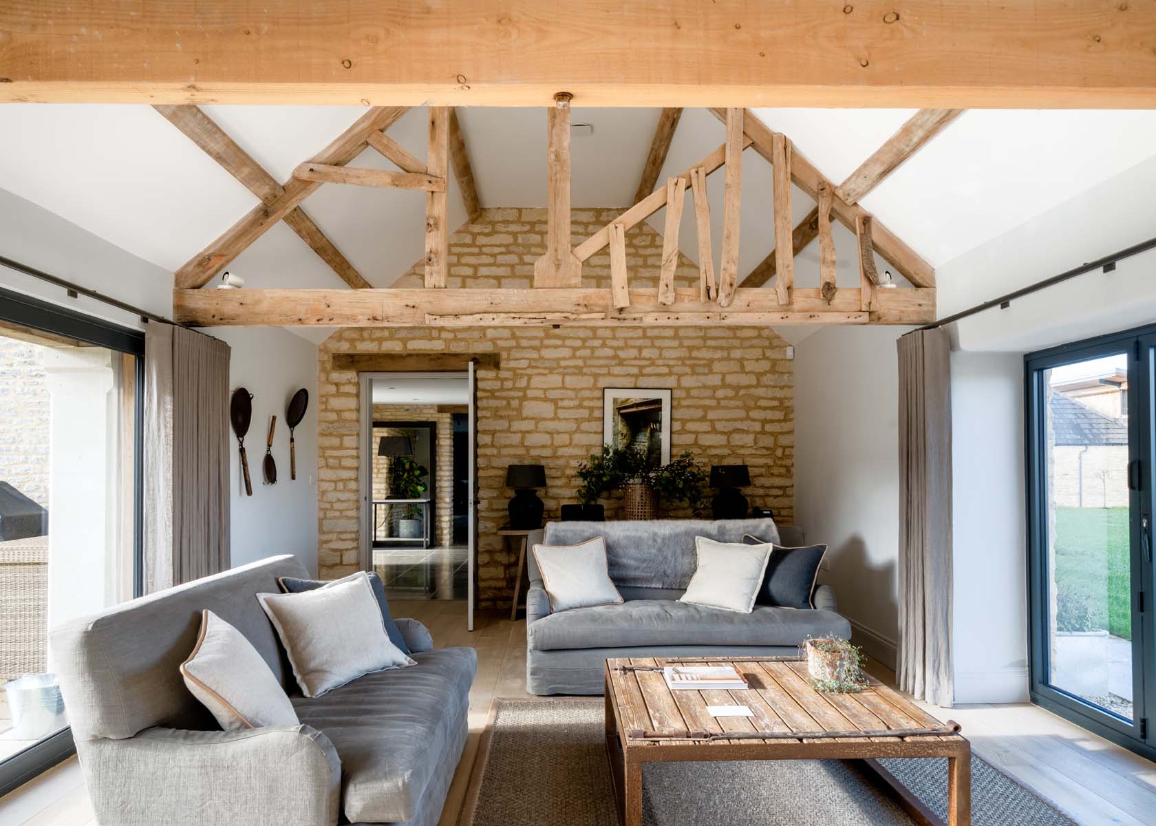 A living area with grey sofas and exposed wooden beams