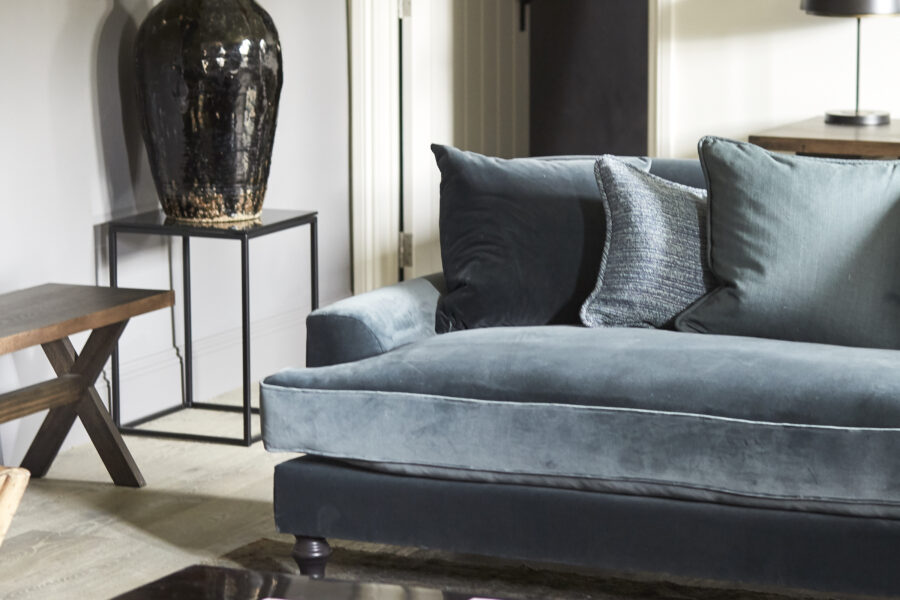 Blue sofa with magazines on wooden coffee table and large vase in the corner
