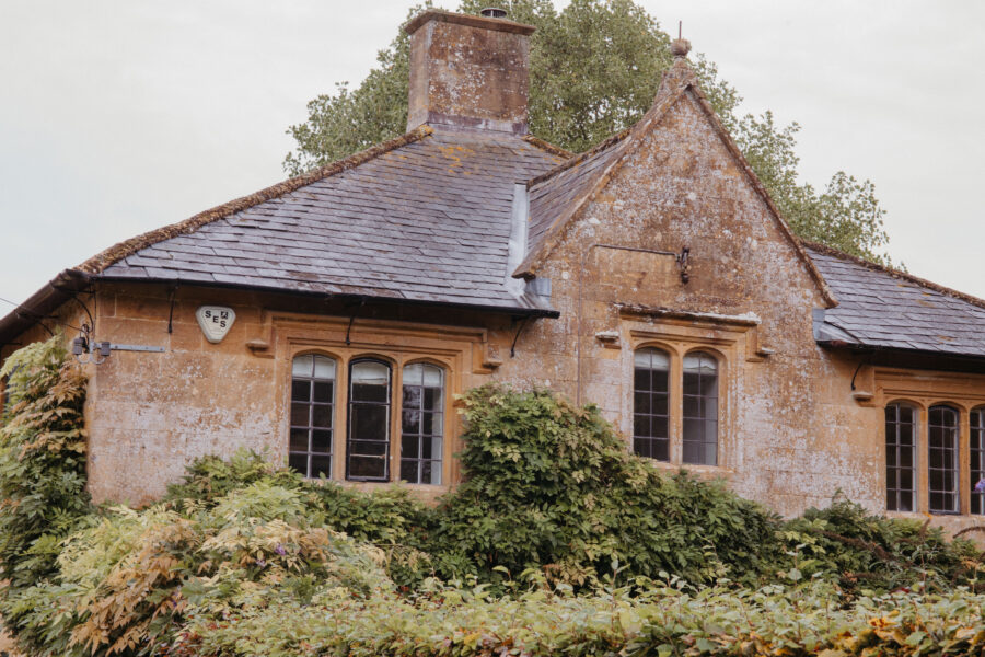 Detail of upstairs and roof of a country house with pretty old windows and climbing plants
