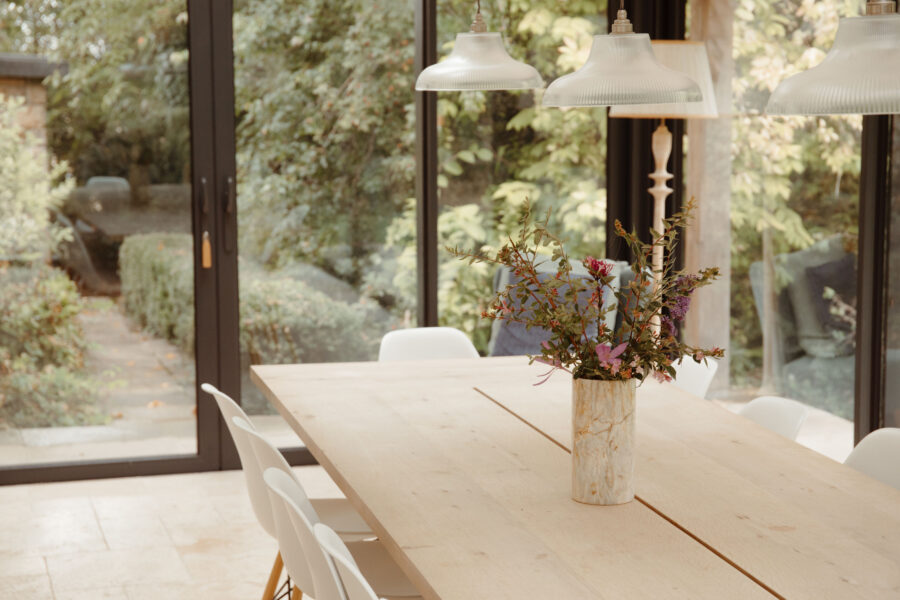 Dining area with floor to ceiling glass windows looking out to the garden