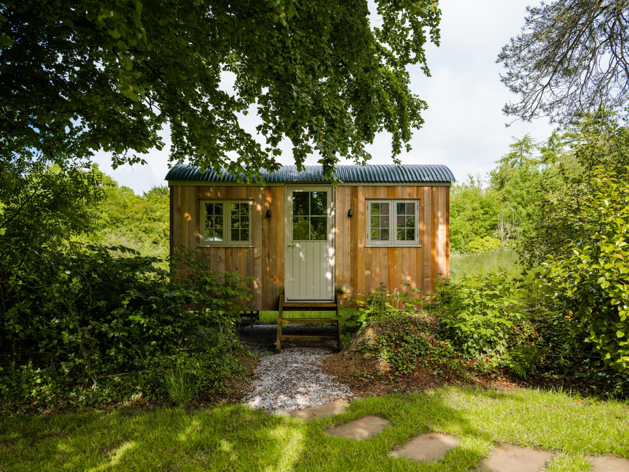 A shepherds hut shaded by a tree