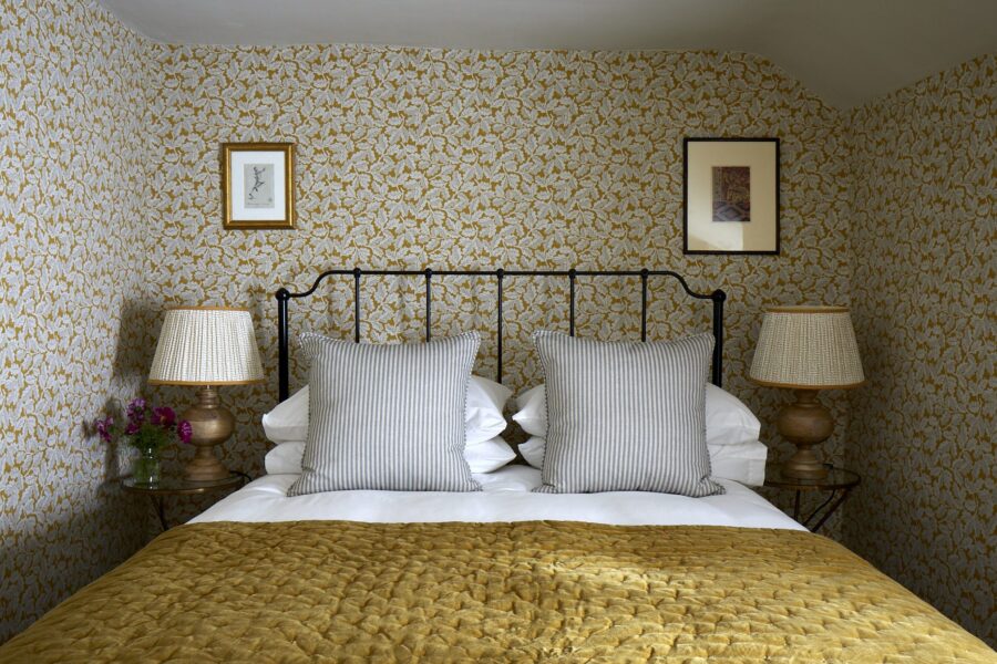 Stylish bedroom with ochre bed spread and designer wallpaper
