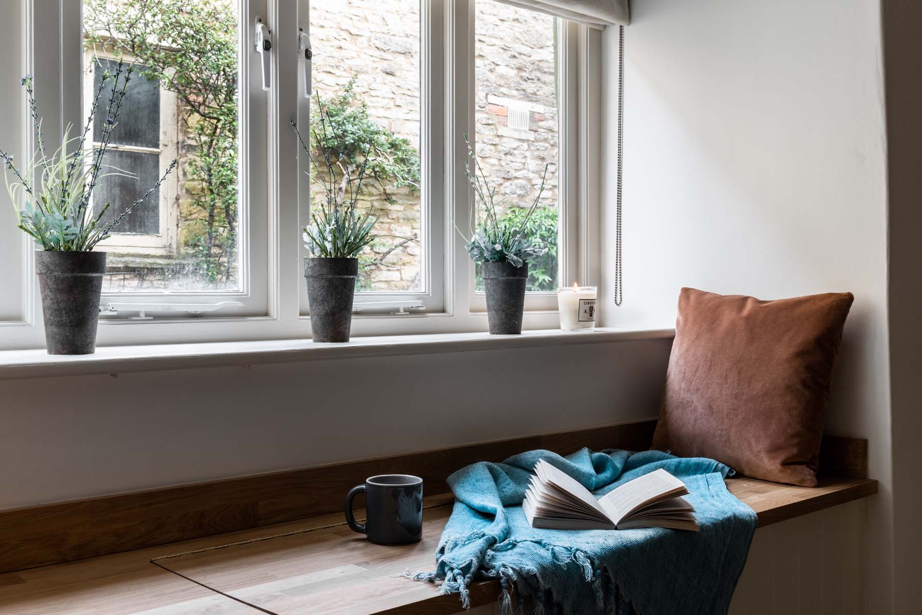 Natural light shines in a window seat with a pink cushion