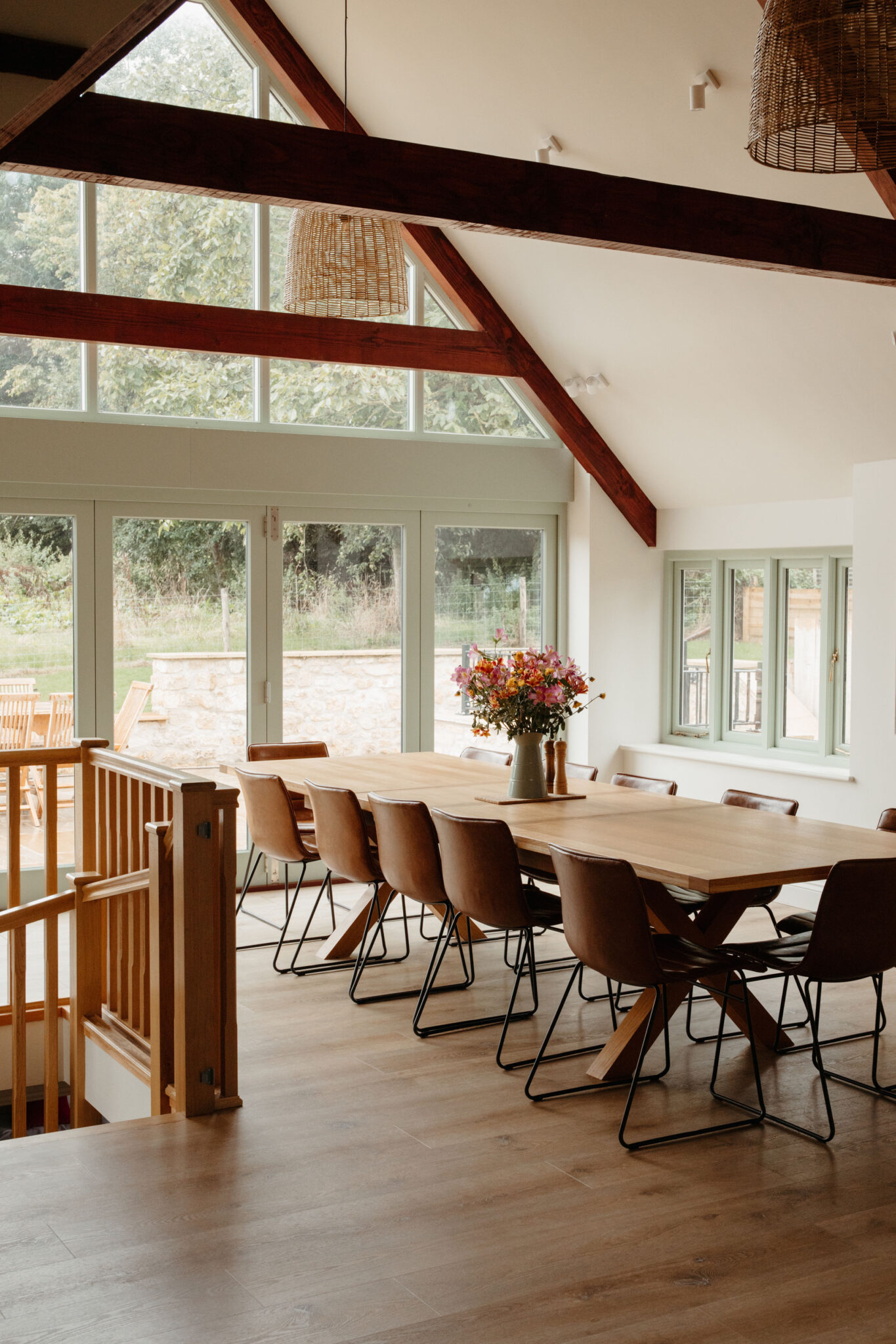 Long wooden dining table with leather chairs in large room with high ceilings and wooden beams