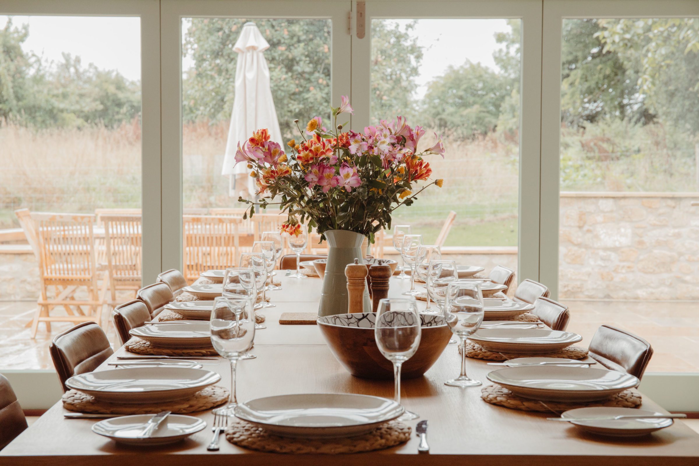 Dining table laid with plates, wine glasses and wild flowers