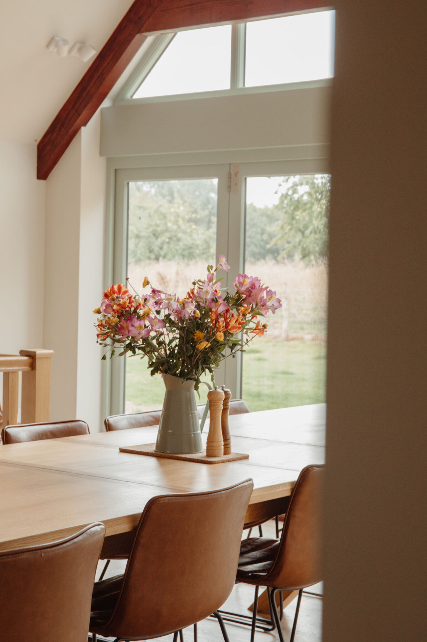 Wild flowers in a green vase on a dining table