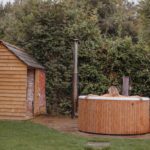 A woman in a wooden hot tub in a garden