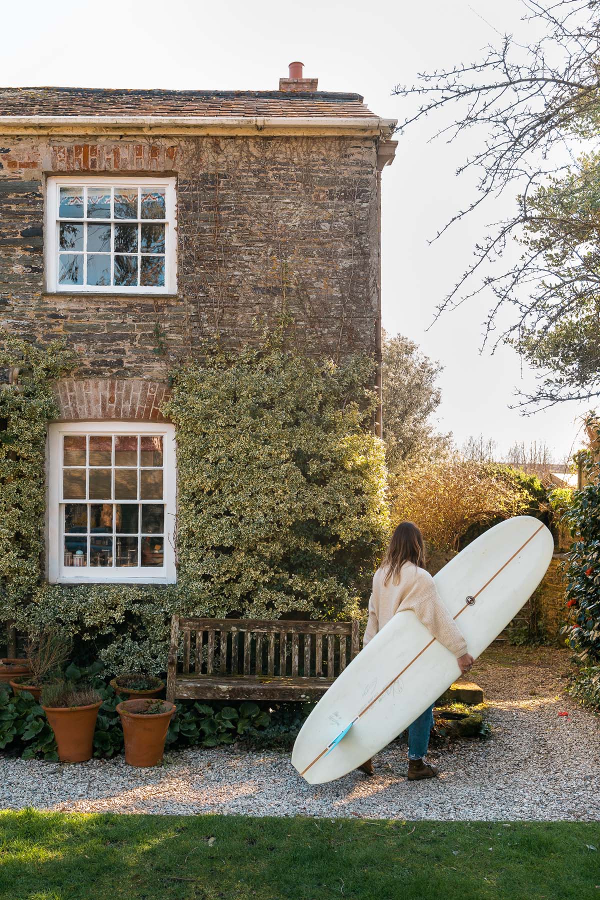 Exterior shot of house with girl carrying surfboard