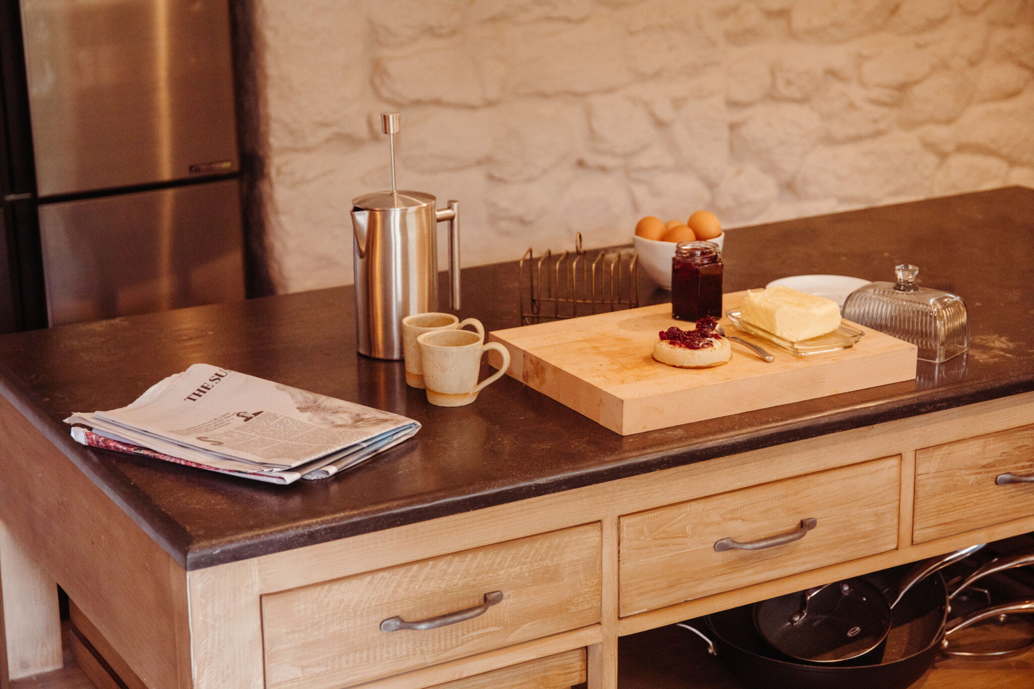 Coffee, papers, crumpets and jam on a kitchen island