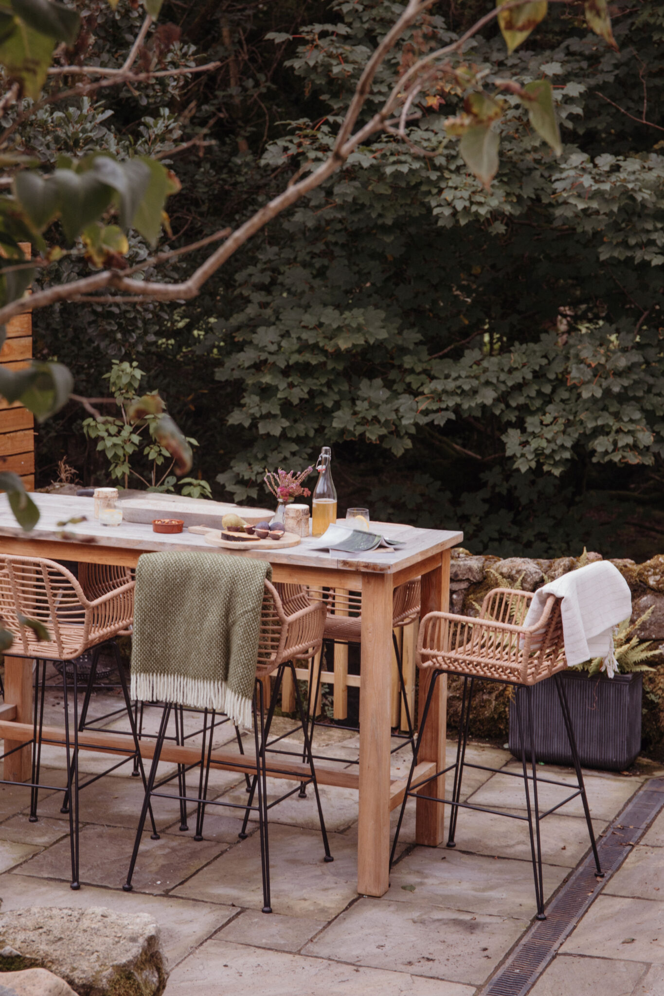 Dining table outside with high wicker chairs and blankets for autumn