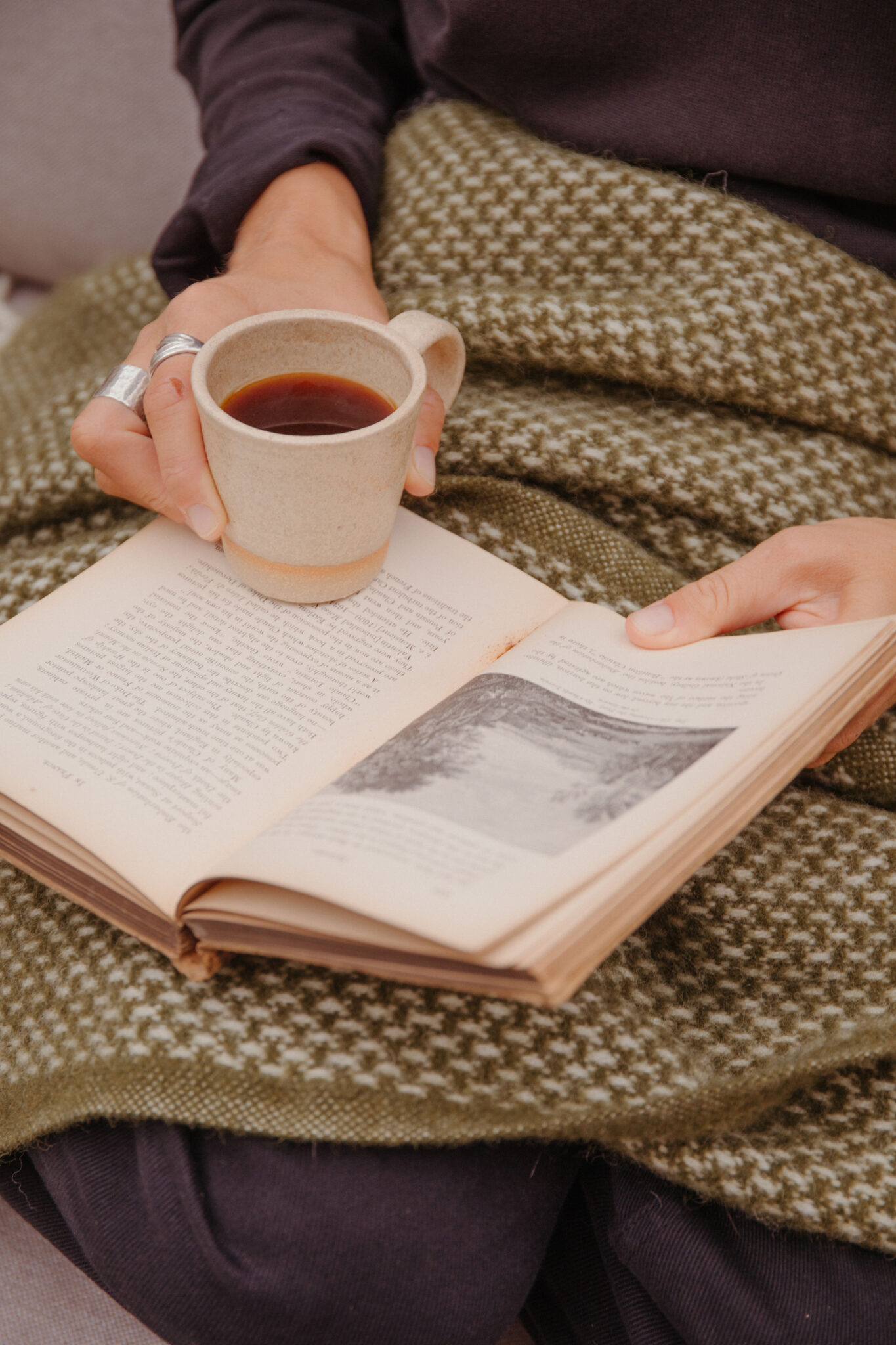 Reading a book with a blanket and a cup of coffee