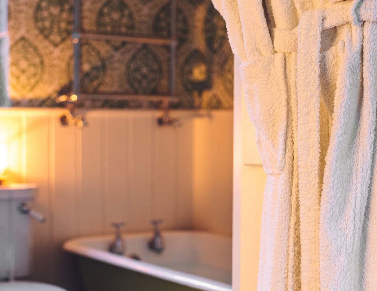Cosy candlelit cottage bathroom with a green roll top tub