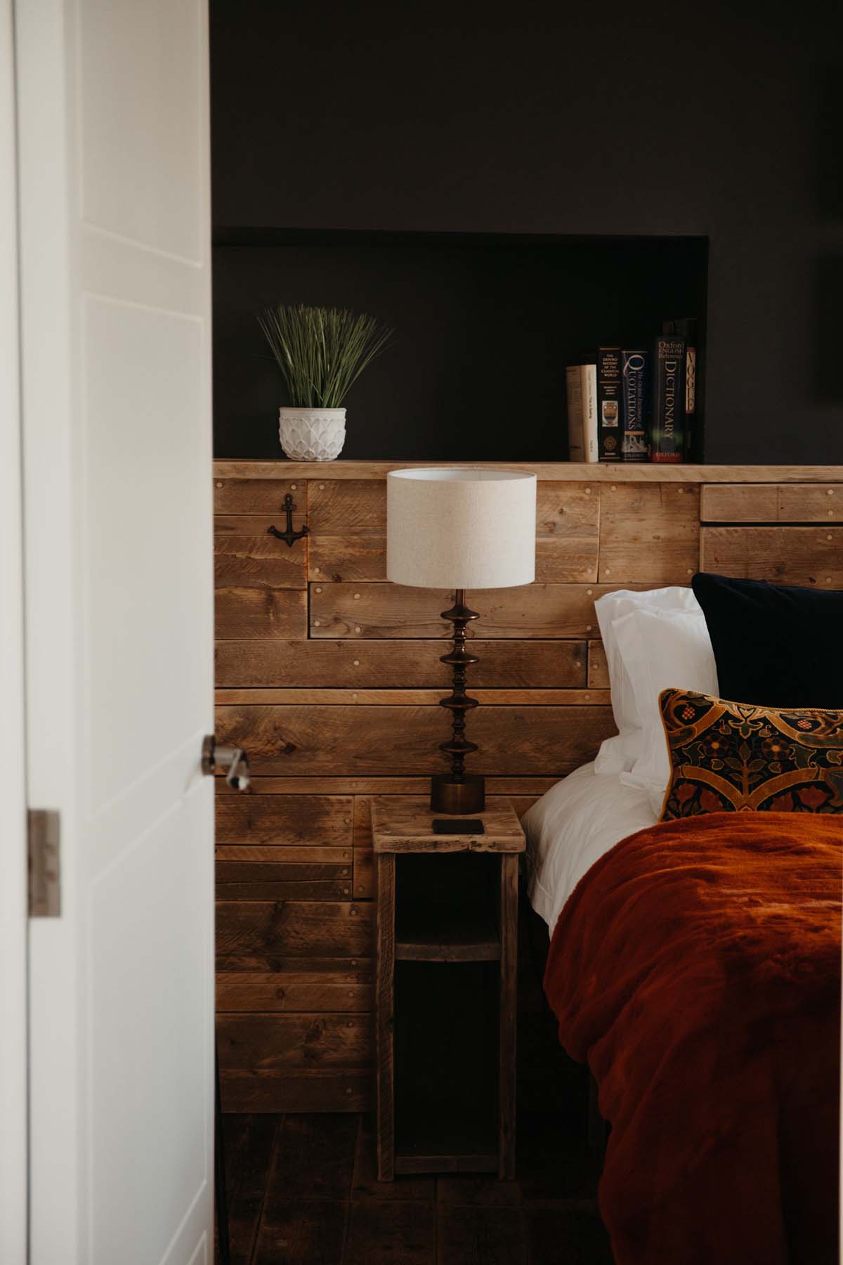 Bedroom with wood cladding and orange velvet throw