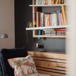 Single bed with wooden book shelf on the wall