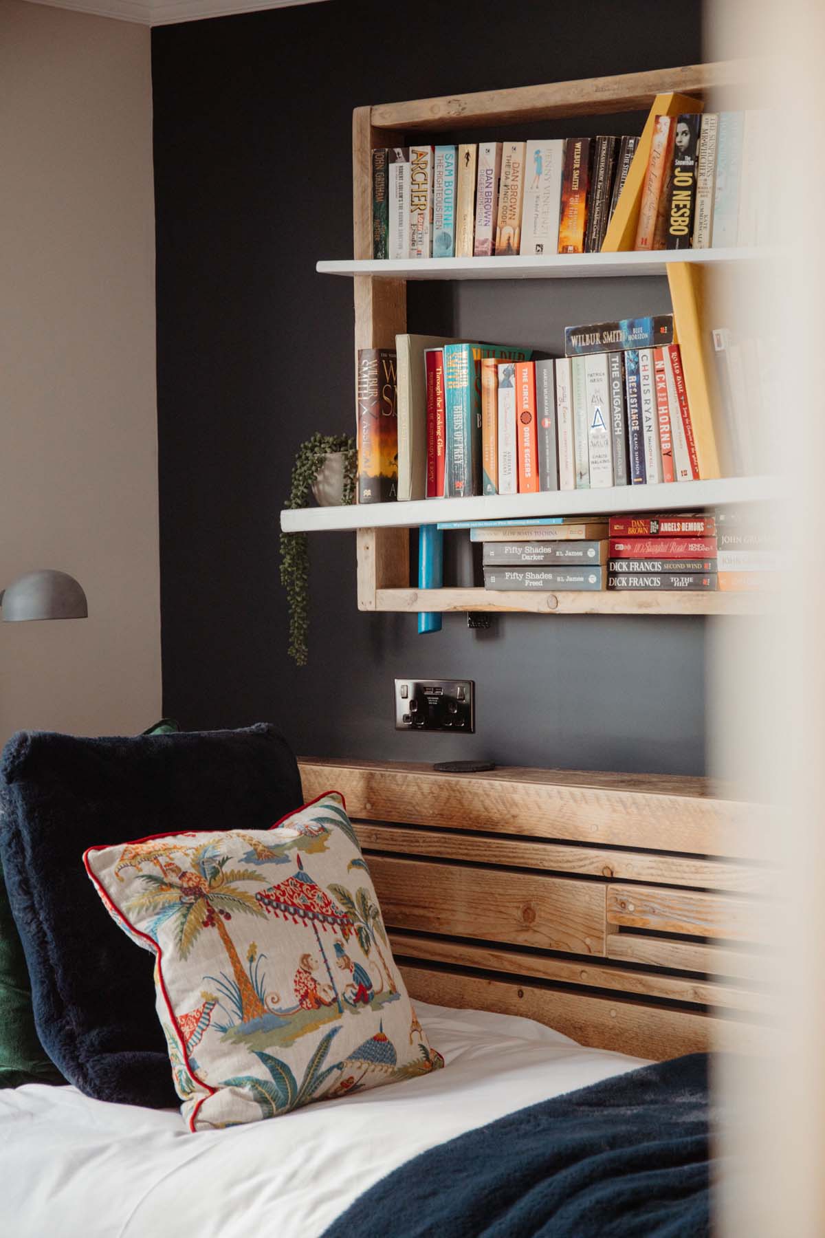 Single bed with wooden book shelf on the wall