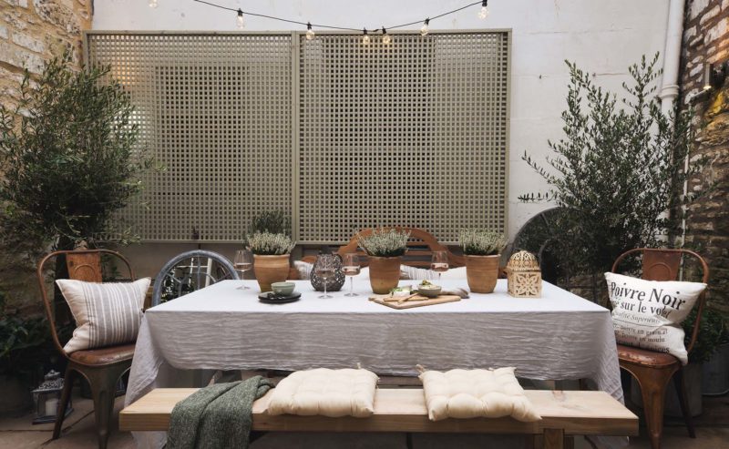 outdoor dining set up with cushions and olive trees