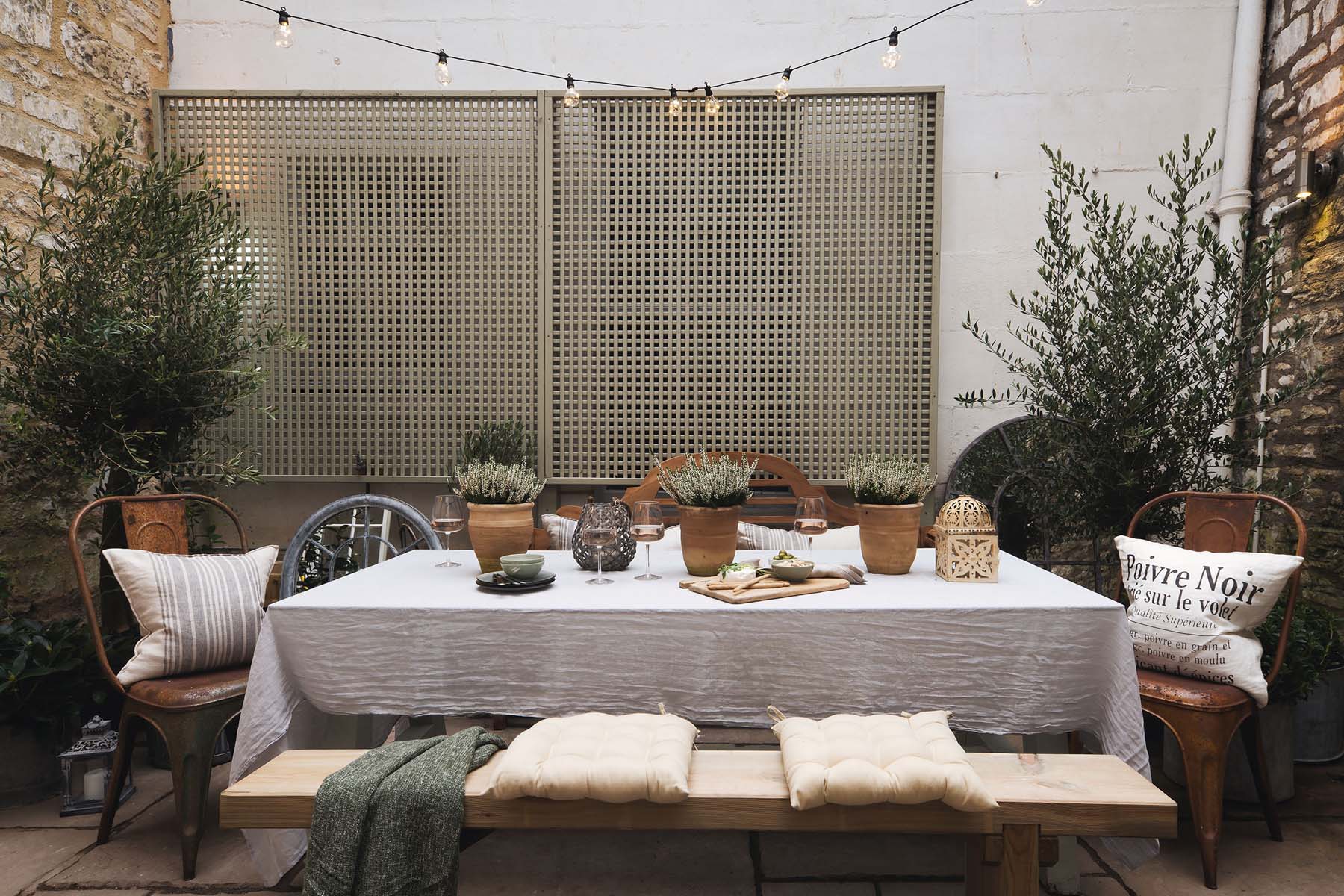 outdoor dining set up with cushions and olive trees