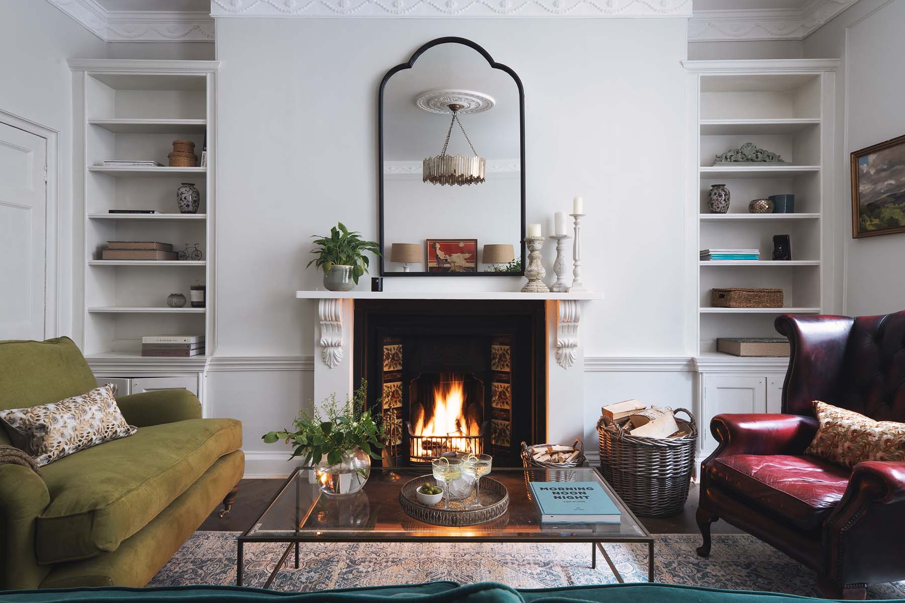 lit open fire with overheard mirror coffee table and sofas