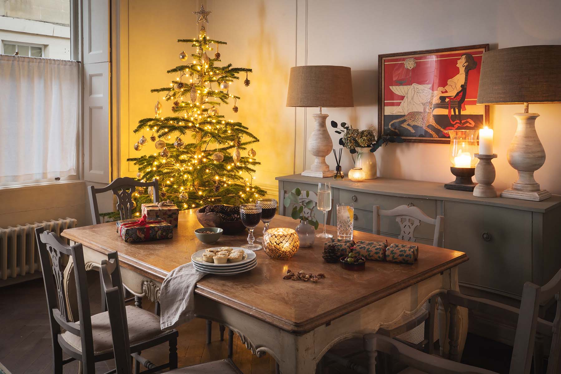 Christmas tree lit up by wooden dining table