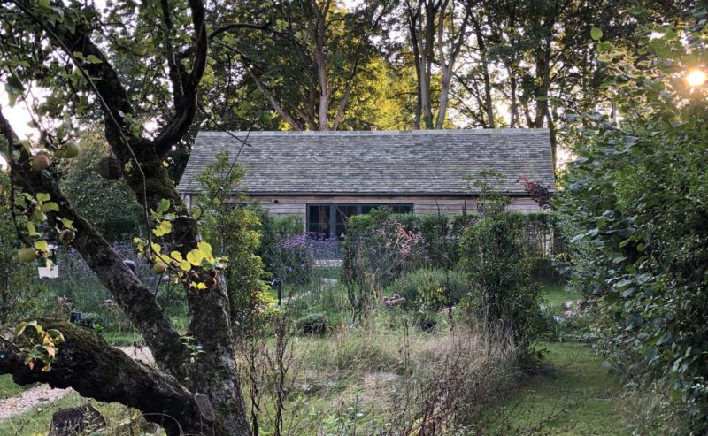 Cottage exterior surrounded by trees and garden