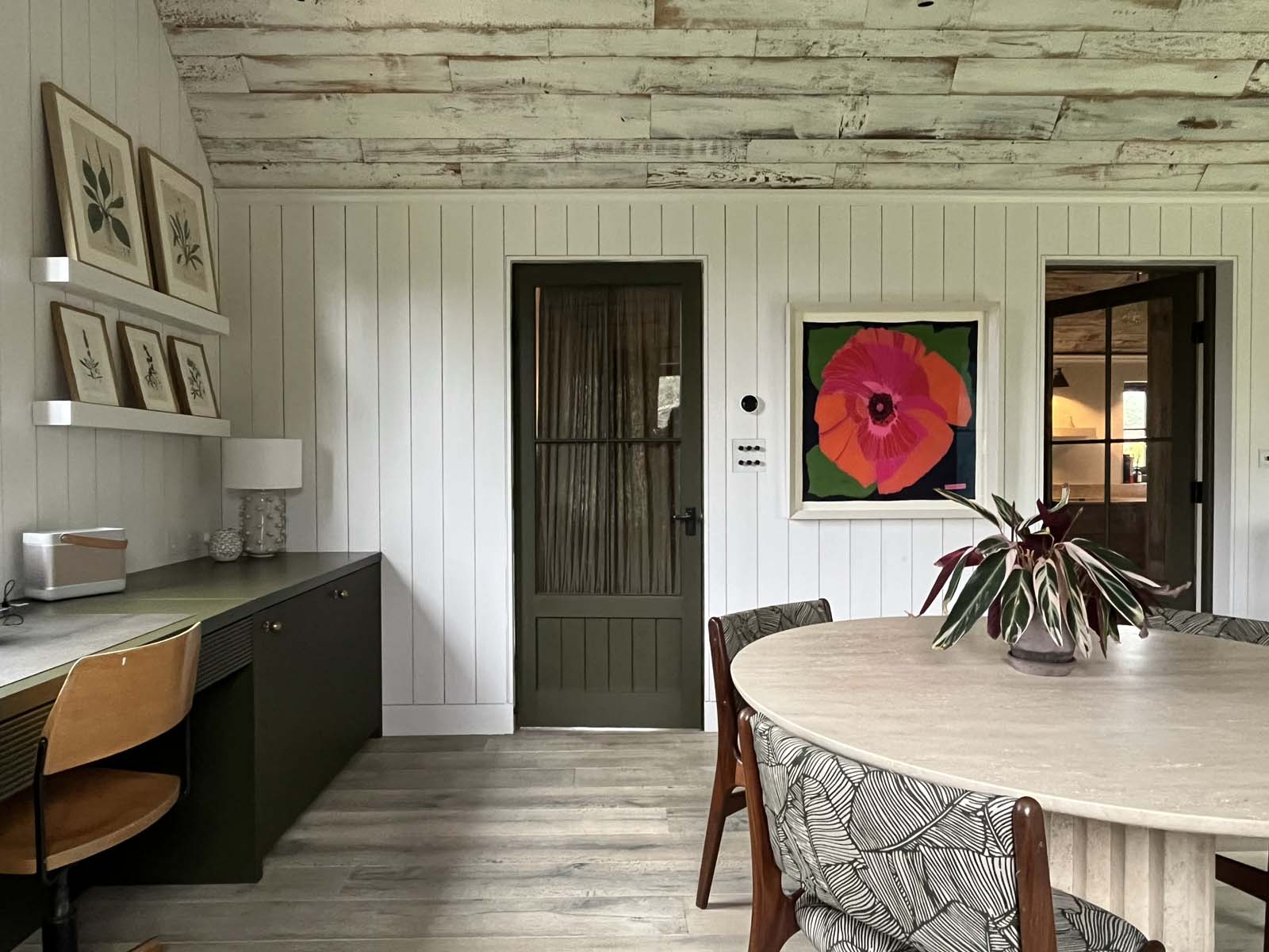 Dining table in wooden panelled room with art work on walls