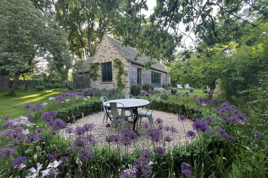 Outdoor dining surrounded by flowers with view to cottage