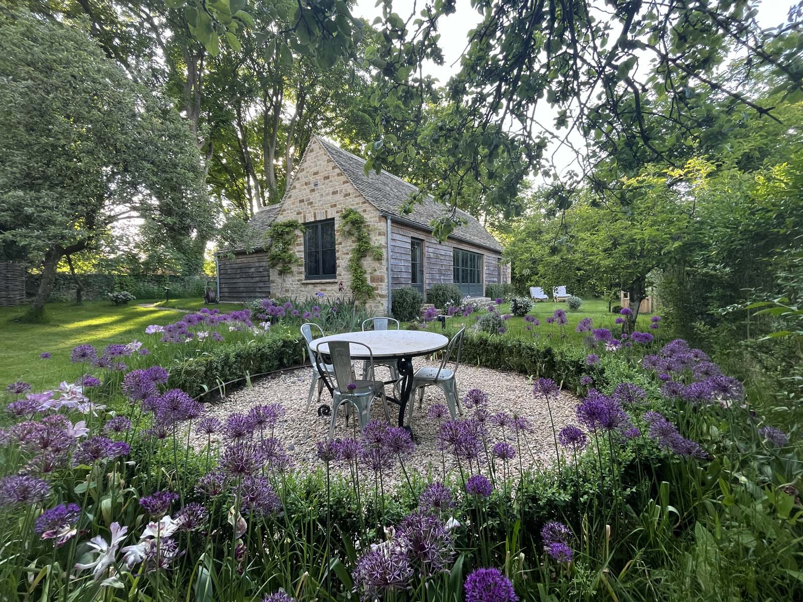 Outdoor dining surrounded by flowers with view to cottage