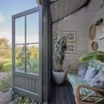rattan sofa in room overlooking garden with open doors