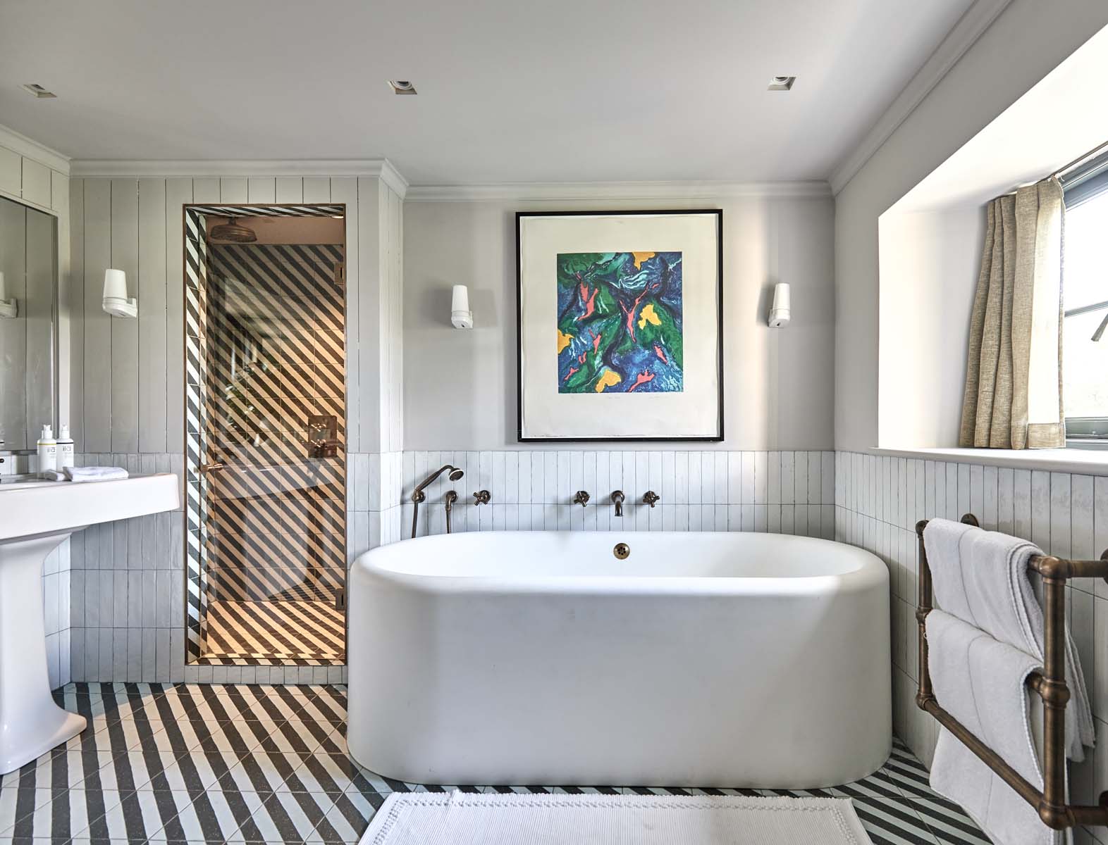 stylish bathroom with bath tub and stripy tiled flooring