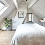 bedroom with sloping loft ceiling with bed facing large windows