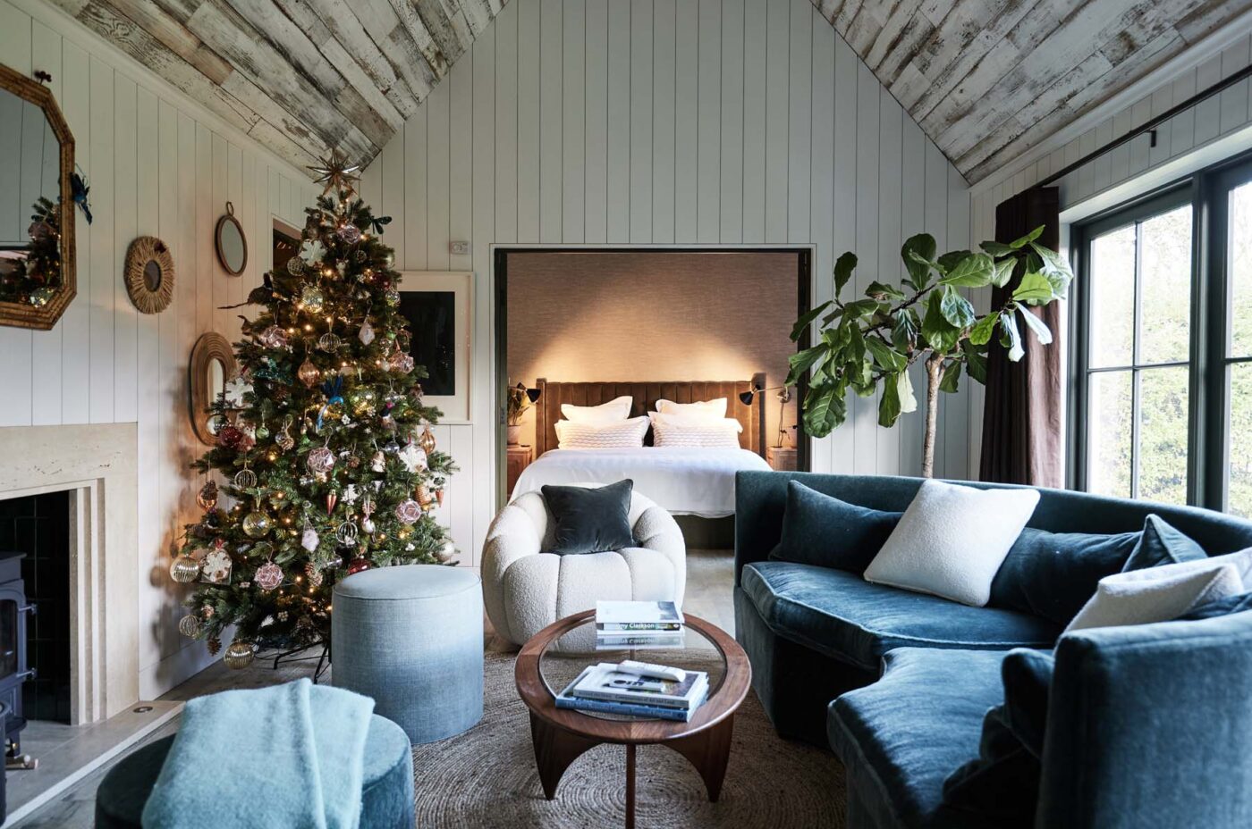 Bedroom opening up onto living room with velvet sofas and wooden ceilings
