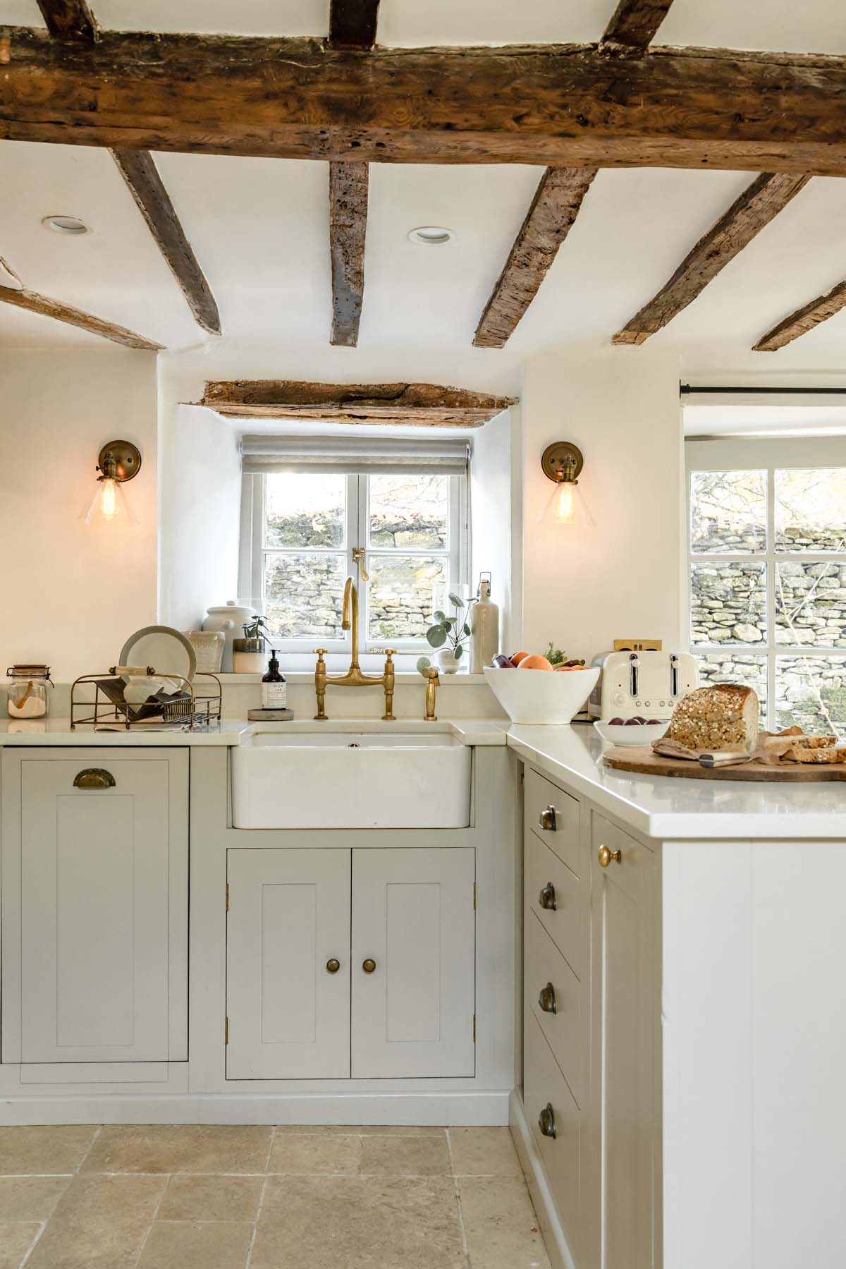 farmhouse style sink and kitchen cabinets with wooden ceiling beams above