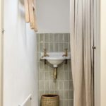 bathroom sink with green tiles and curtain
