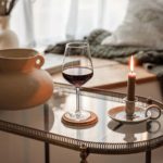 close up of red wine in a glass next to candle