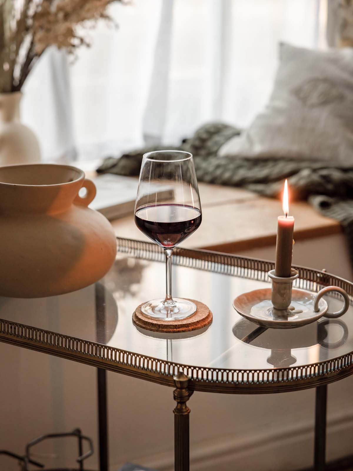 close up of red wine in a glass next to candle