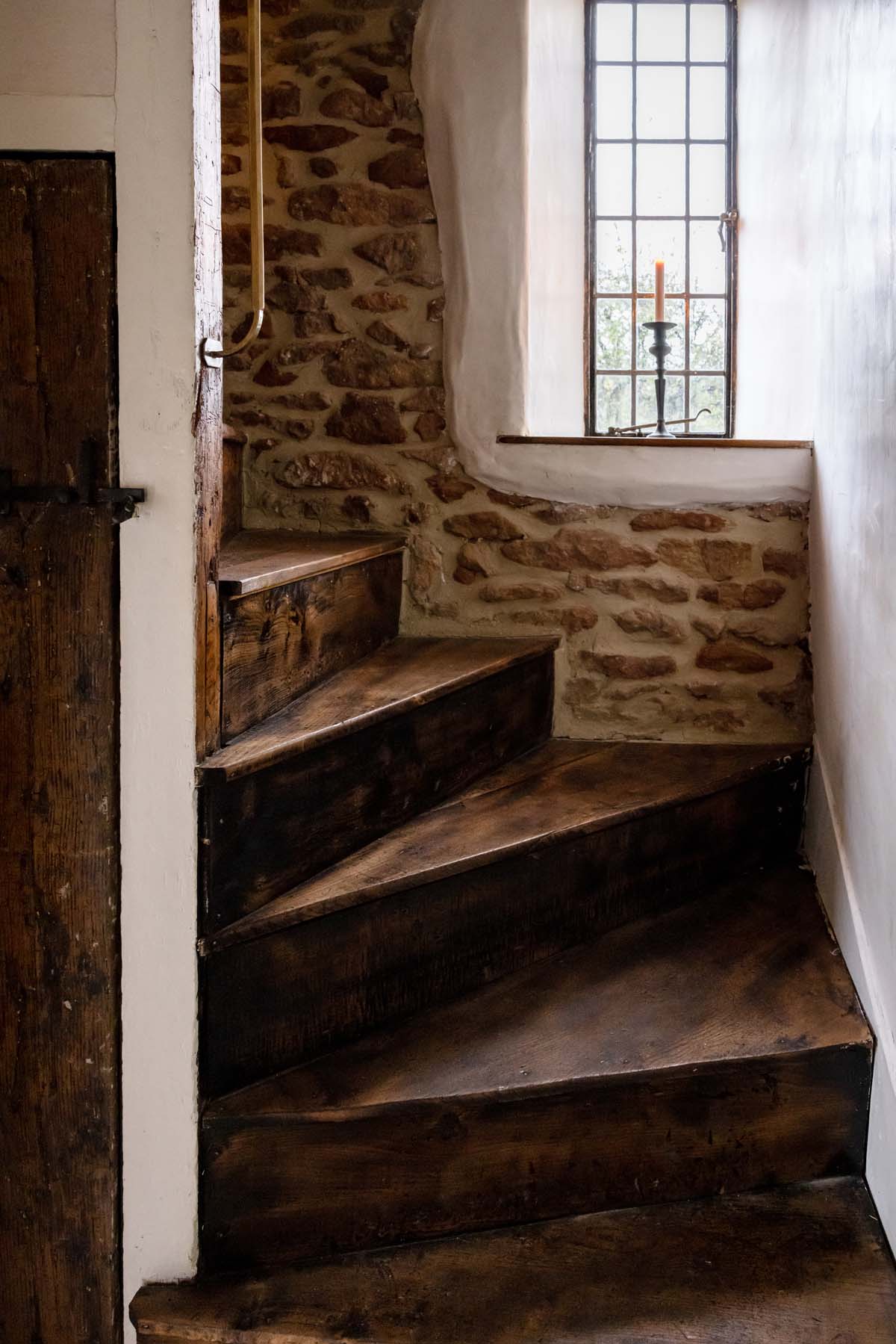 wooden spiral staircase with open brick wall behind