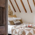 Cottage bedroom exposed beams and a patchwork quilt